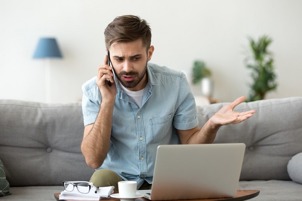 mężczyzna rozmawia przez telefon przed komputerem
